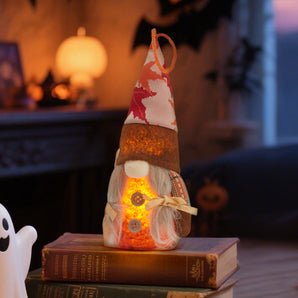 Thanksgiving gnome plush on books, red-and-white star hat with glowing belly LED