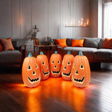Mehrere orange LED-Halloweenlaternen mit Kürbisgesichtern, jeweils gelb leuchtende Aussparungen