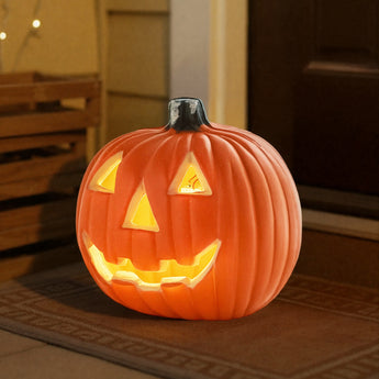 Orange LED pumpkin lantern on patio mat, jack-o'-lantern face glowing