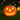 Orange LED pumpkin lantern on grass, jack-o'-lantern smile glowing from eyes and mouth