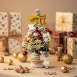 Tabletop Christmas tree with LED lights, gold bow, “Merry Christmas” sign, red and gold ornaments, dolls