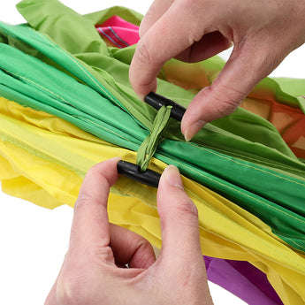 Hands pulling open and securing green, yellow and pink fabric panels of tunnel