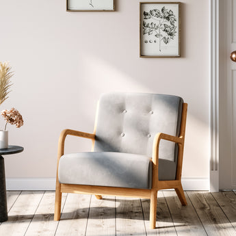 Grey tufted linen upholstered armchair with buttoned back and wooden arms, angled view.