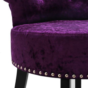 Close-up of dark purple velvet dressing stool with silver stud trim along seat edge
