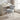 Light gray plush upholstered chair with rounded backrest and white tapered legs
