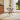 Glass-top metal table with X-frame legs on a round rug, small size