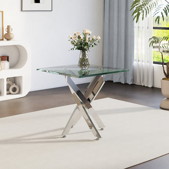 Glass-top metal table with angled chrome legs and clear tabletop, vase on top