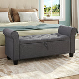Gray upholstered storage bench ottoman with side armrests and button-tufted cushion