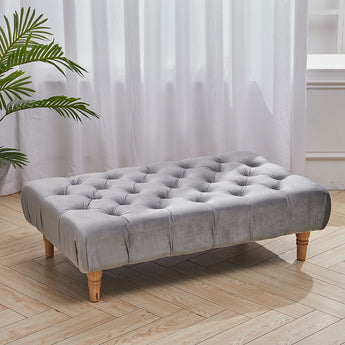 Rectangular velvet footstool with tufted top and gray upholstery