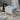 Linen upholstered ottoman footstool in light blue-gray with tufted lid and wooden legs
