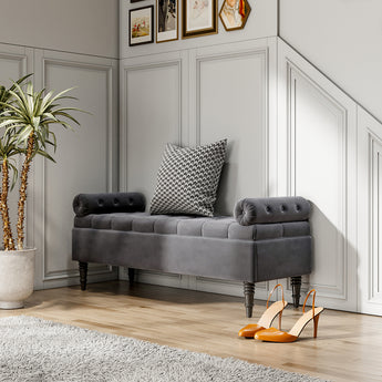 Grey velvet storage bench with tufted armrests, button detailing, and wooden legs