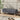 Dark gray linen upholstered bench with wooden legs, low cushioned seat.