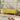 Yellow linen upholstered bench with wooden legs, low cushioned seat.