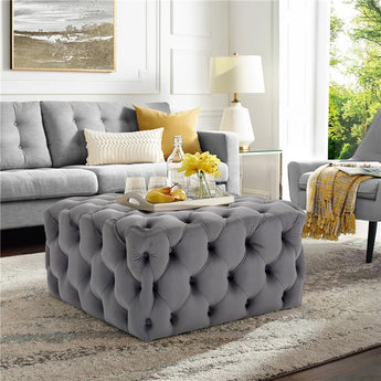 Grey velvet square footstool with button-tufted upholstery and padded top