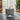 Round light gray velvet storage ottoman with flat top and black tapered legs