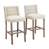 Pair of light cream linen bar stools with button-tufted backs and wooden legs