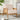 Cream cushioned armchair with rattan back panels and light wood legs