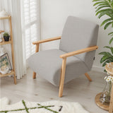 Grey chenille armchair side view: rounded armrests and tapered light wood legs.