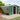 Dark green metal garden storage shed with side door open and stacked items inside