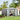 Gray metal lockable garden storage shed with double doors open, tools visible inside.