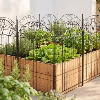 Black decorative garden fence with arched scrollwork top and vertical bars in outdoor yard