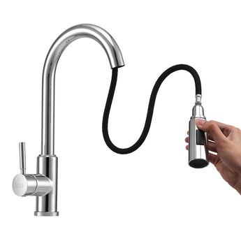 Hand holding chrome pull-down sprayer hose attached to kitchen faucet