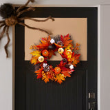 Autumn wreath with orange maple leaves, pinecones, mini pumpkins, and berry clusters