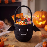 Black Halloween treat bucket with handle, smiling face, and candy snack fill