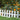 White plastic lawn border fence pickets with stakes, surrounding orange flowers and greenery