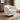 Cream upholstered swivel armchair with wide rounded arms and dark circular base.