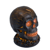 Halloween skull decoration with cracked black resin and orange glowing eyes and teeth
