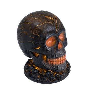 Halloween skull decoration with cracked black resin and orange glowing eyes and teeth