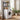 Black 2-tier over-washer storage rack with shelves holding bottles above a front-load dryer