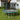 Trampoline enclosure net and teal-green ladder, gray mat on cushioned green base