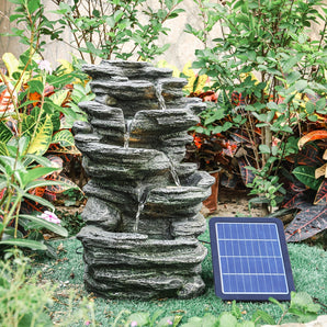 Solar-powered cascading rock water fountain with flowing streams and attached solar panel