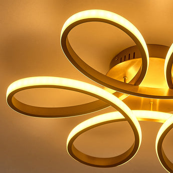 Close-up of golden LED semi-flush mount ceiling light with glowing circular ring channels