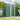 Green metal storage shed with sloped roof, front door closed