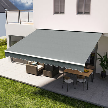 Grey manual retractable patio awning with scalloped valance extended over patio