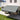 Grey manual retractable patio awning with scalloped valance extended over patio