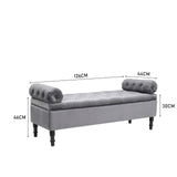 Grey velvet upholstered storage bench with tufted ends and turned wooden legs